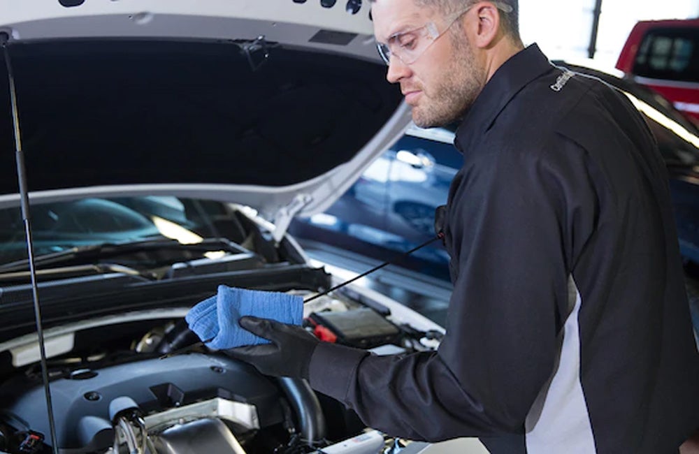 Certified technician performing a professional oil service on a vehicle